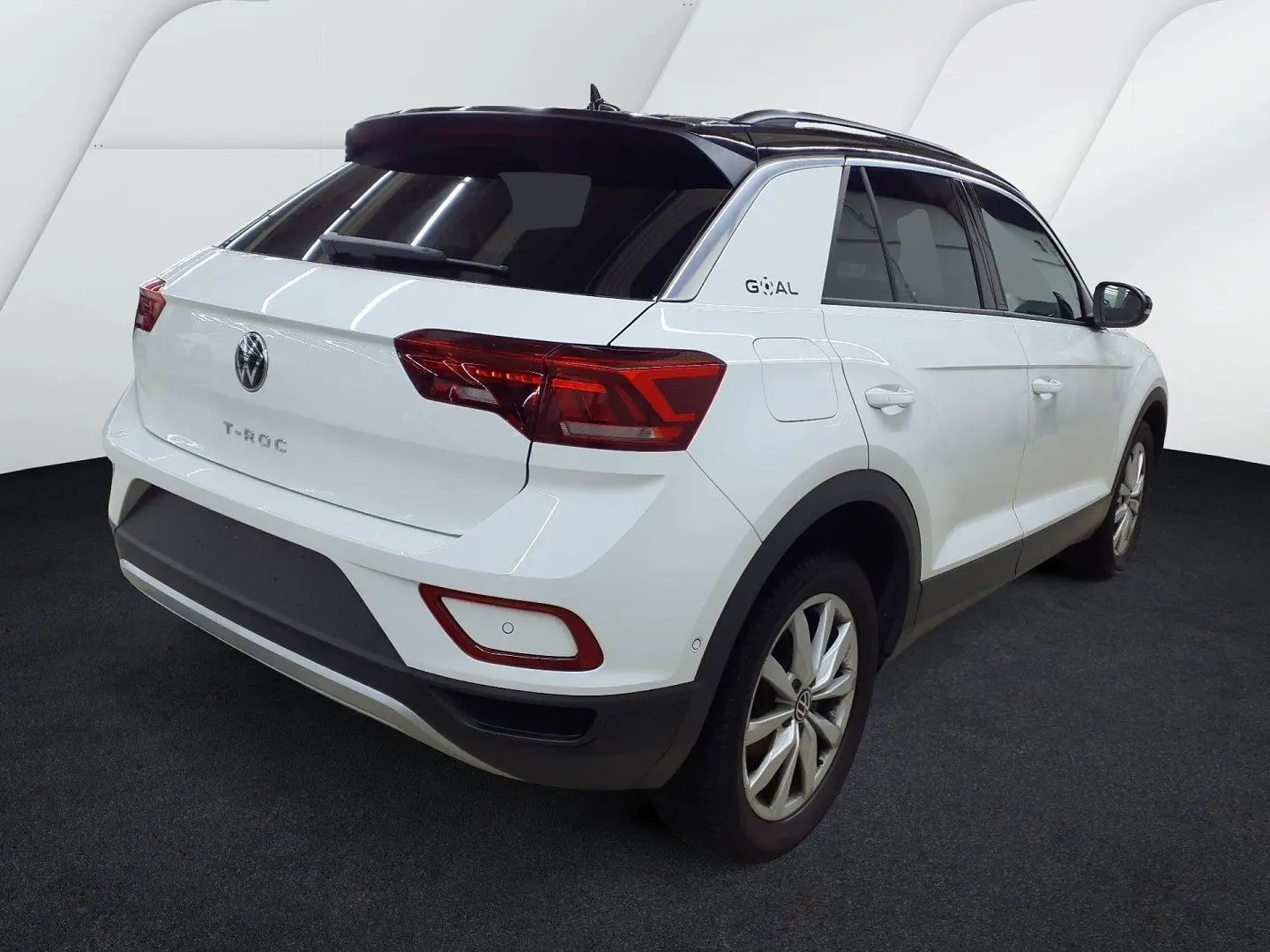 Vue 3/4 arrière droite d’un Volkswagen T-Roc blanc pure avec toit noir, feux arrière LED et jantes alliage.