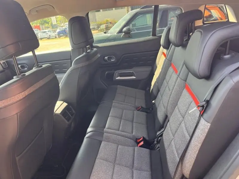 Vue intérieure côté gauche des sièges arrière gris et noirs avec appuie-têtes individuels et ceintures rouges d’un Citroën C5 Aircross 2019.