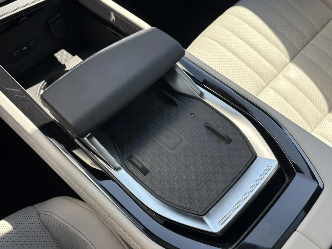 Gros plan sur la console centrale avec chargeur smartphone à induction et accoudoir textile gris sable dans Renault Espace Bleu Nocturne.