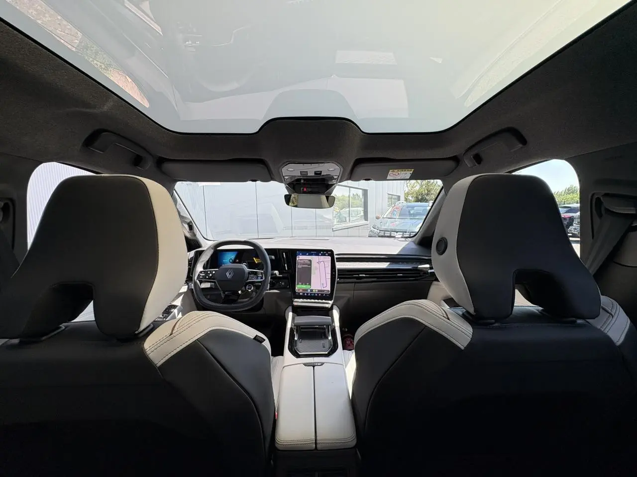 Vue intérieure arrière du Renault Espace 2025 bleu nocturne, avec toit panoramique et écran tactile central visible.