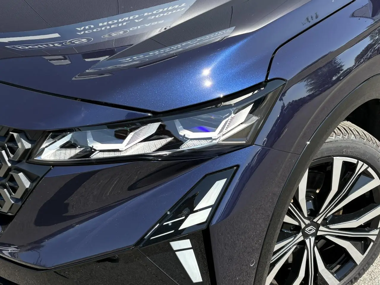 Gros plan sur l'avant droit bleu nocturne du Renault Espace 2025, mettant en valeur le phare LED matrix et la jante alliage 20 pouces.
