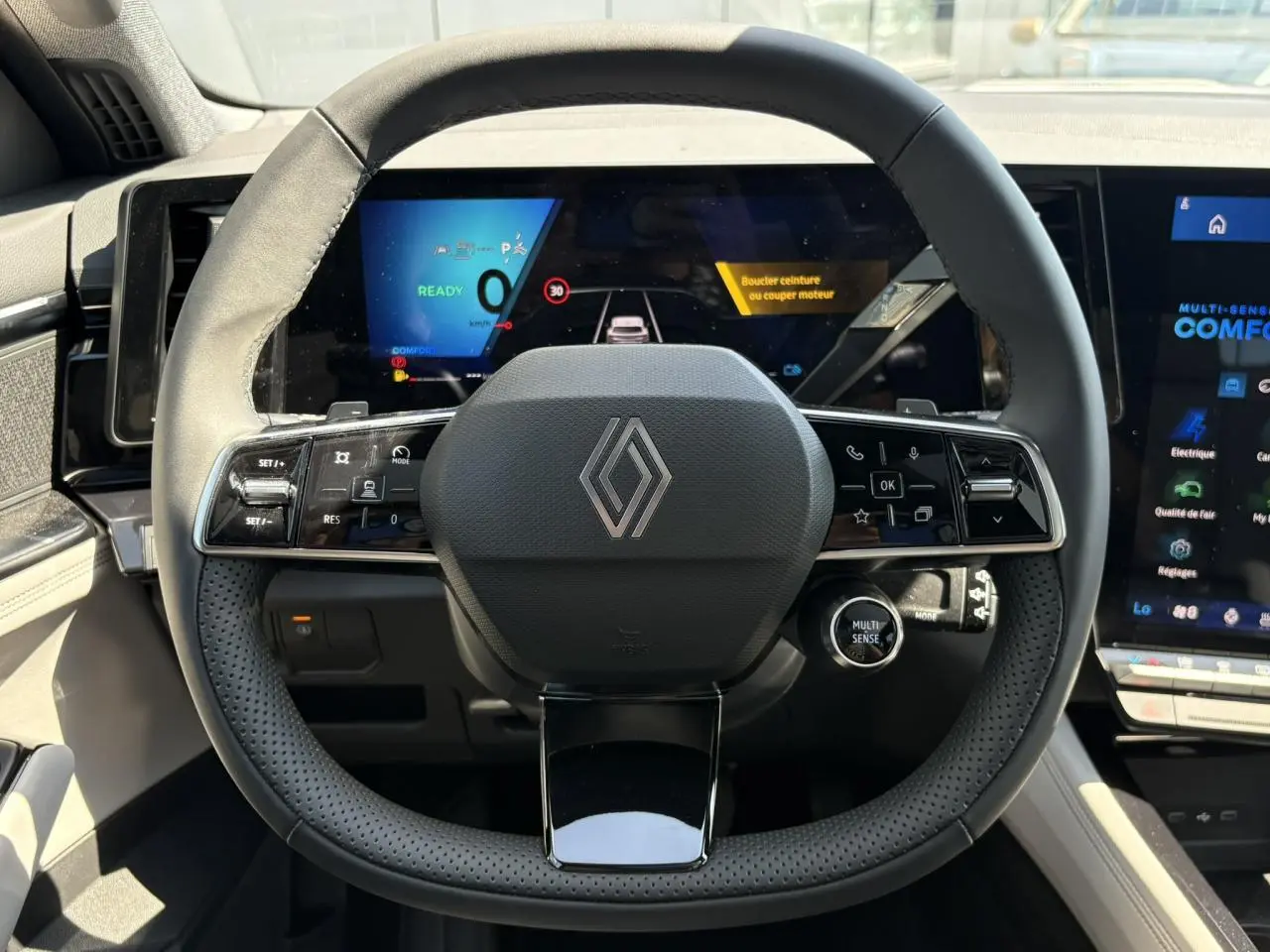Vue frontale du volant noir perforé de la Renault Espace 2025 avec affichage numérique et commandes intégrées.