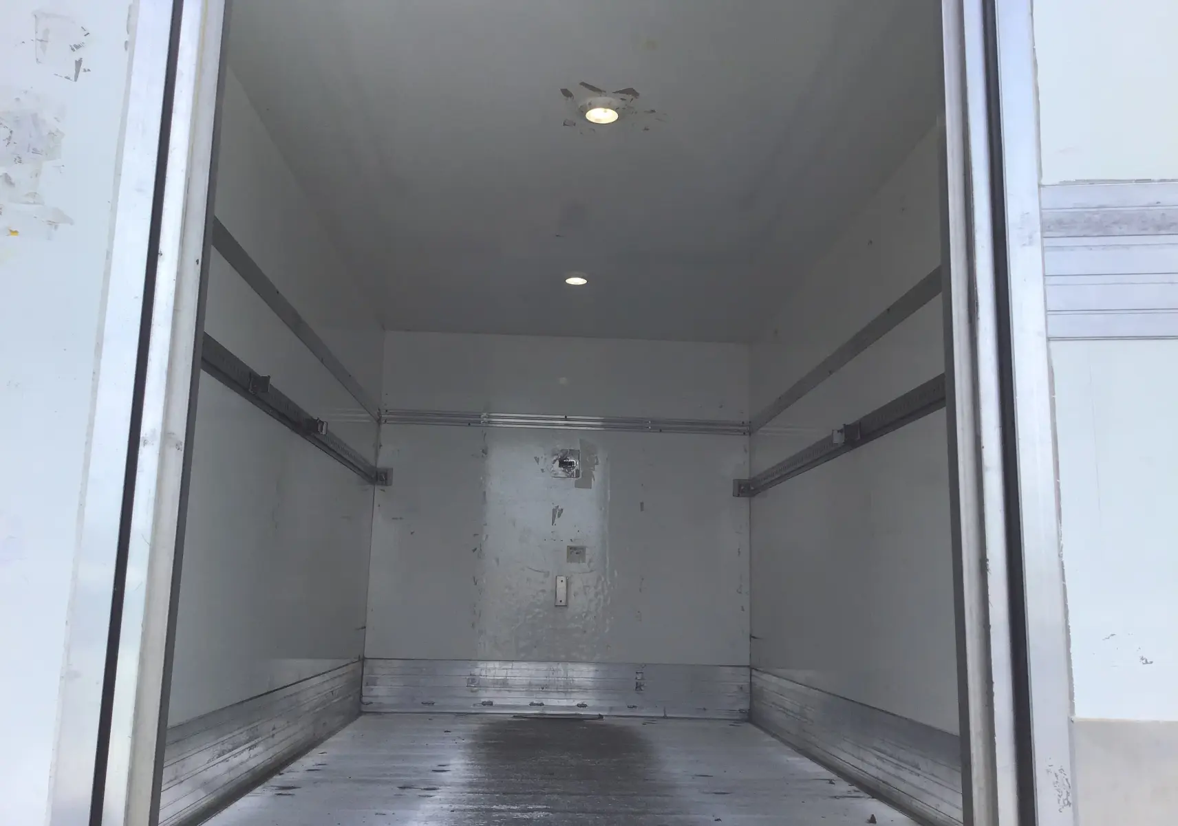 Vue intérieure de la caisse aluminium du Volkswagen Crafter bleu, montrant le plancher et l’éclairage au plafond.