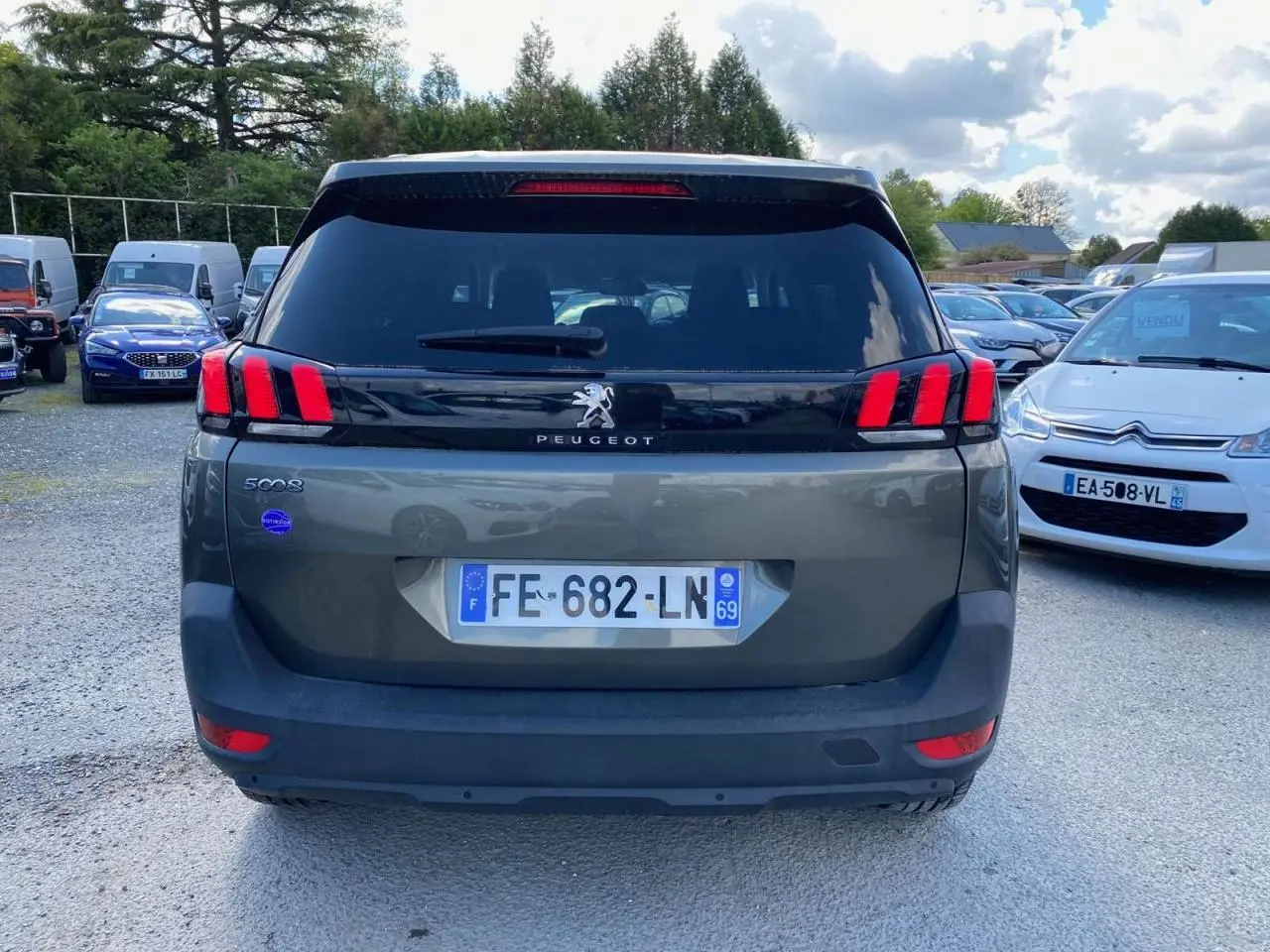 Vue arrière d'un Peugeot 5008 gris clair avec feux arrière à griffes rouges et lunette arrière surteintée.