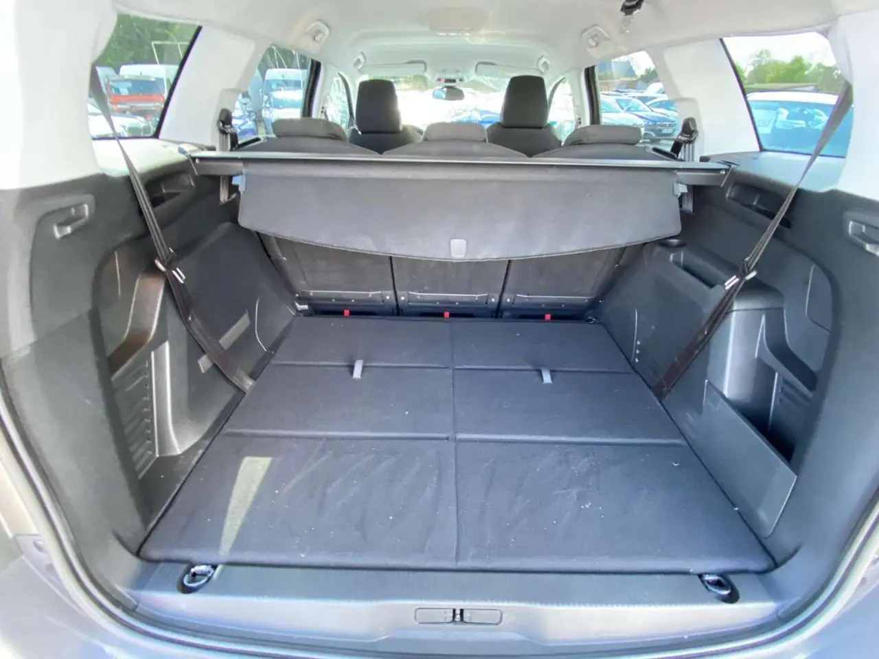 Coffre ouvert du Peugeot 5008 gris clair, montrant les sièges arrière rabattus et la tablette cache-bagages déployée.