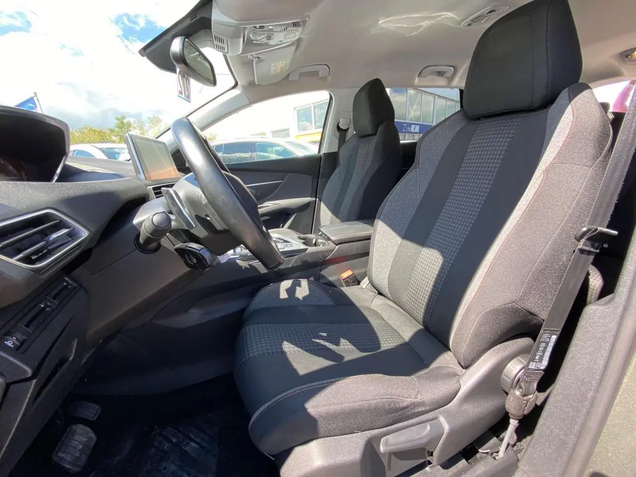 Vue intérieure côté conducteur du Peugeot 5008 gris clair de 2019, mettant en valeur la sellerie tissu et le tableau de bord moderne.