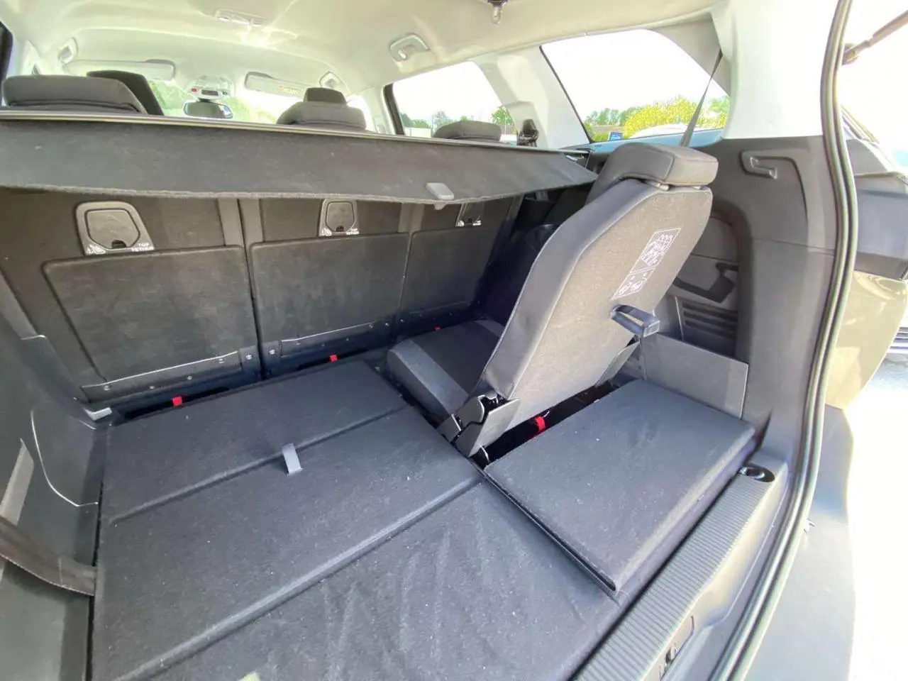 Vue arrière du coffre du Peugeot 5008 gris clair avec siège rabattable et banquette arrière en tissu noir.