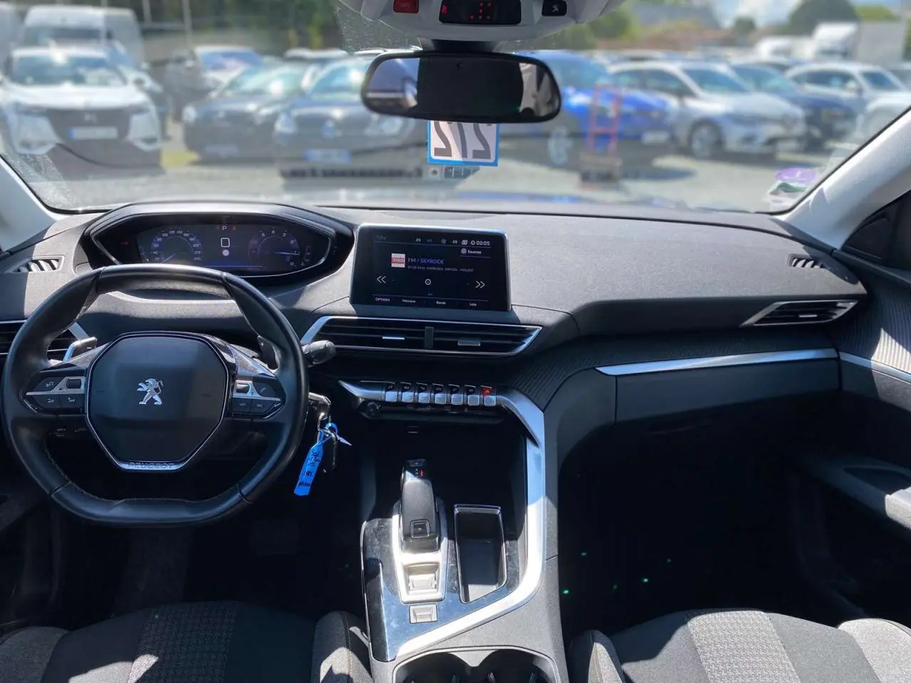 Vue intérieure avant du Peugeot 5008 gris clair, avec tableau de bord moderne et écran tactile central.