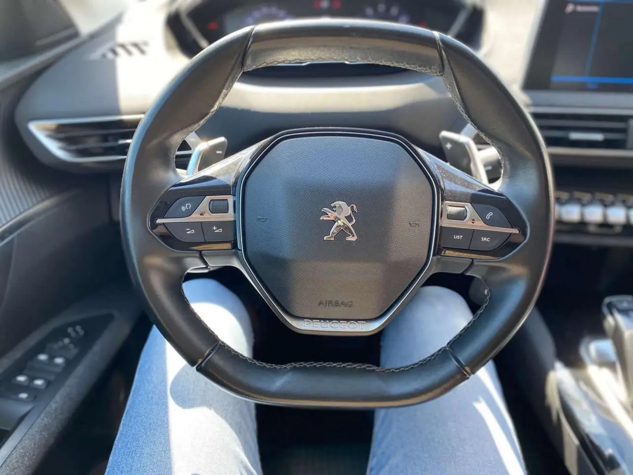 Vue rapprochée du volant cuir noir du Peugeot 5008 2019 avec commandes intégrées et logo lion central.