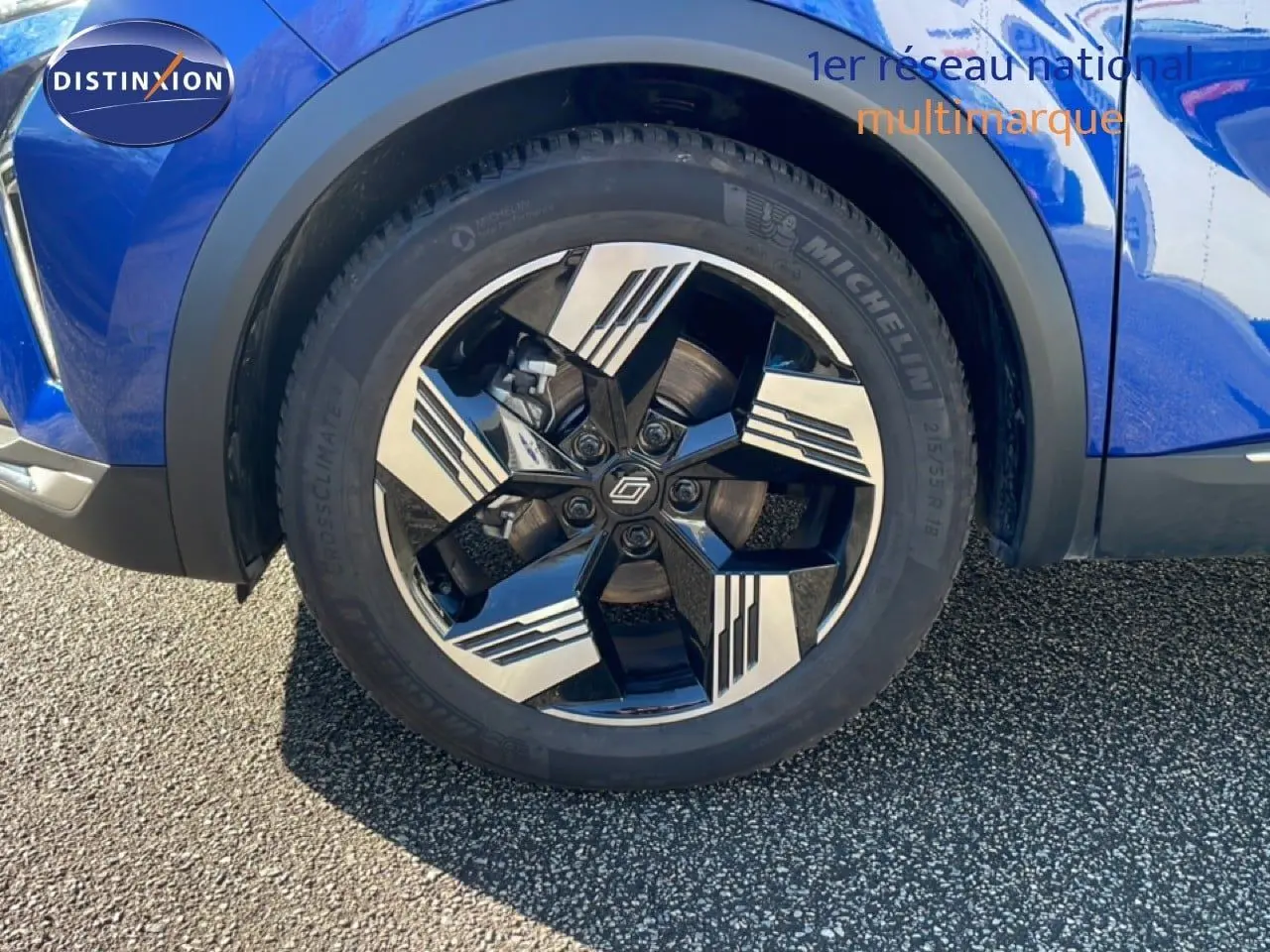Gros plan sur la roue avant droite d’une Renault Symbioz bleu iron metal avec jante noire et argentée au design moderne.