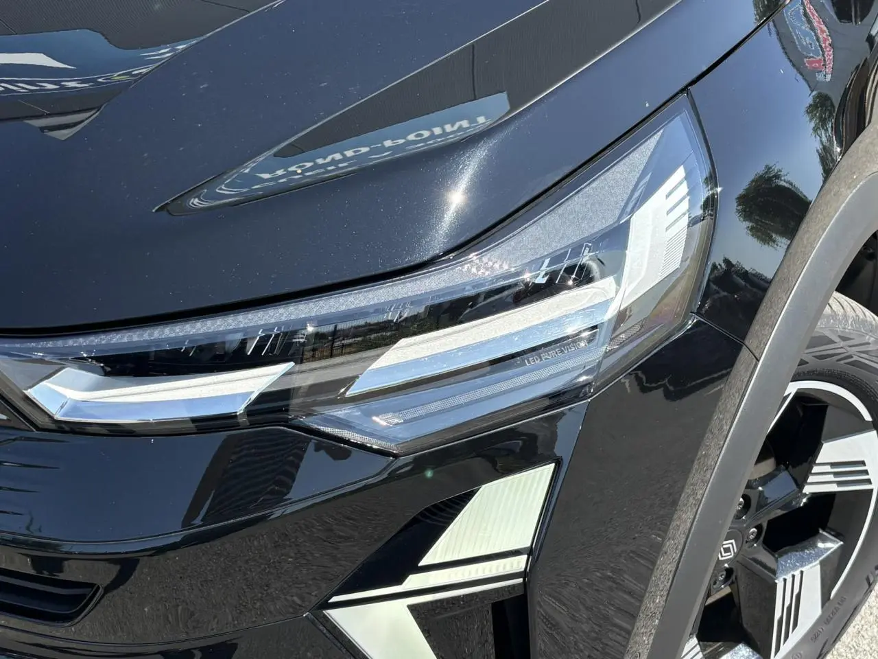 Gros plan sur le phare avant droit et la jante 18" du Renault Symbioz noir étoilé, soulignant les détails LED Pure Vision.