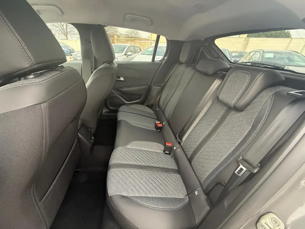 Vue intérieure arrière côté droit montrant les sièges arrière gris avec surpiqûres et ceintures de sécurité de la Peugeot 208 Hybrid 145 Allure 2025.