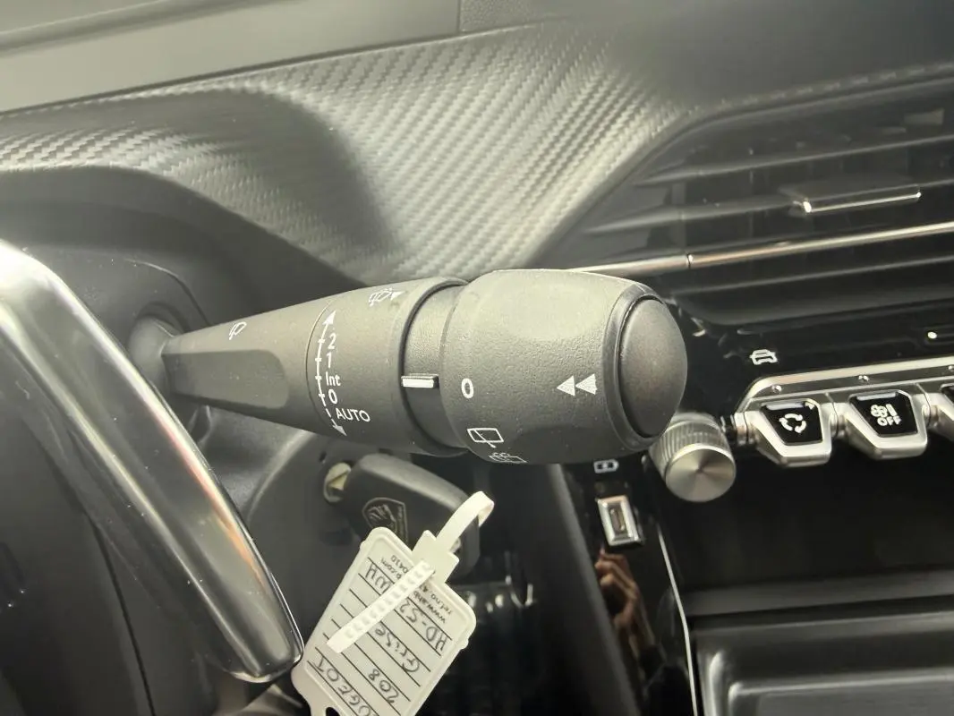 Gros plan sur la commande d’essuie-glace et la partie droite du tableau de bord carbone d’une Peugeot 208 gris 2025.