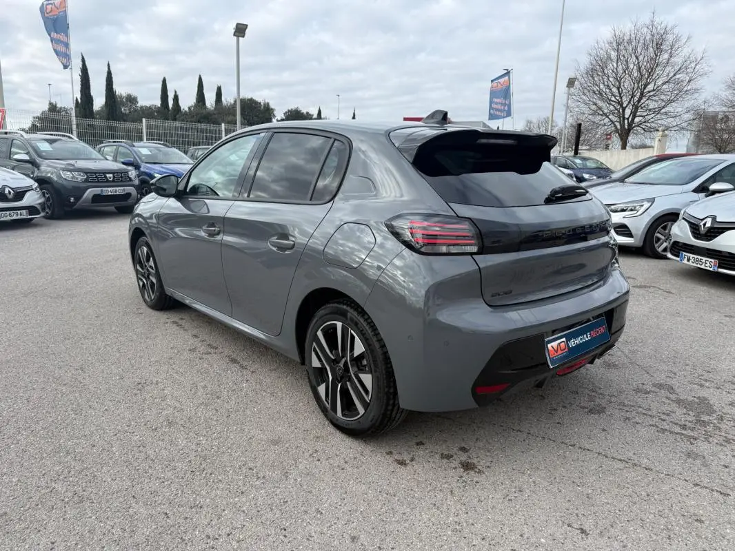 Peugeot 208 Hybrid 145 gris vue 3/4 arrière droit, jantes alliage 16 pouces et antenne requin noire.