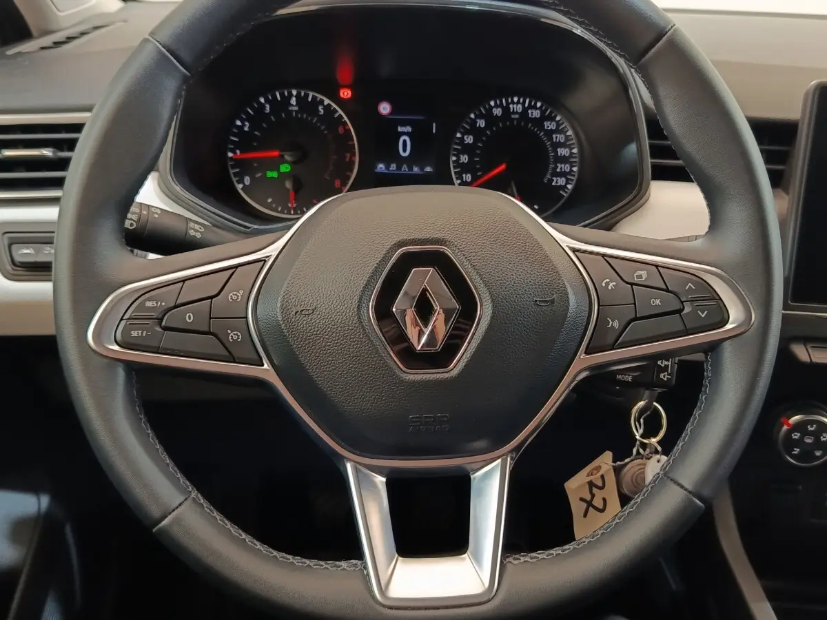 Vue rapprochée du volant cuir multifonctions noir de la Renault Clio Evolution TCe 90 avec tableau de bord en arrière-plan.