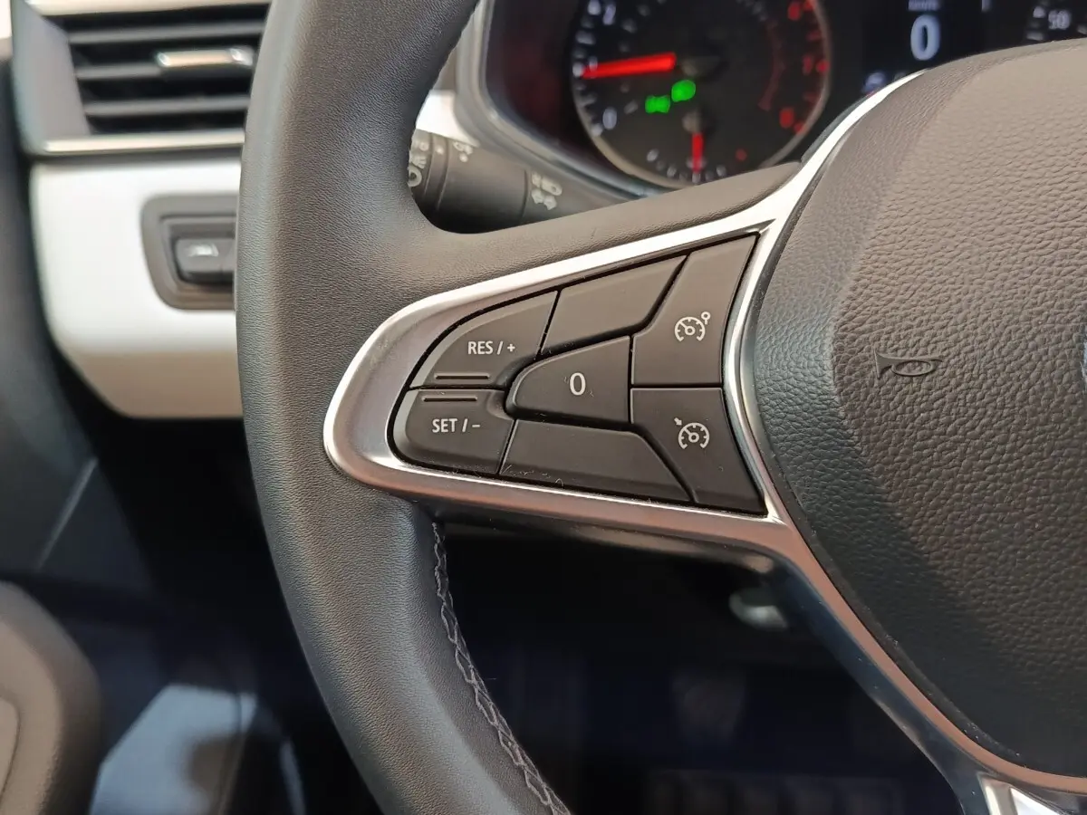 Gros plan sur le volant cuir synthétique noir de la Renault Clio 2023 avec commandes du régulateur de vitesse.