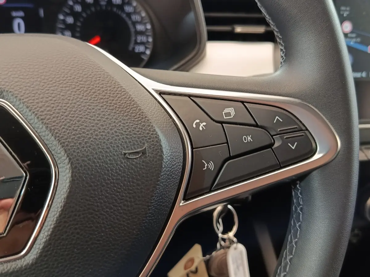 Gros plan sur le volant cuir synthétique multifonctions de la Renault Clio Evolution TCe 90 blanche de 2023.