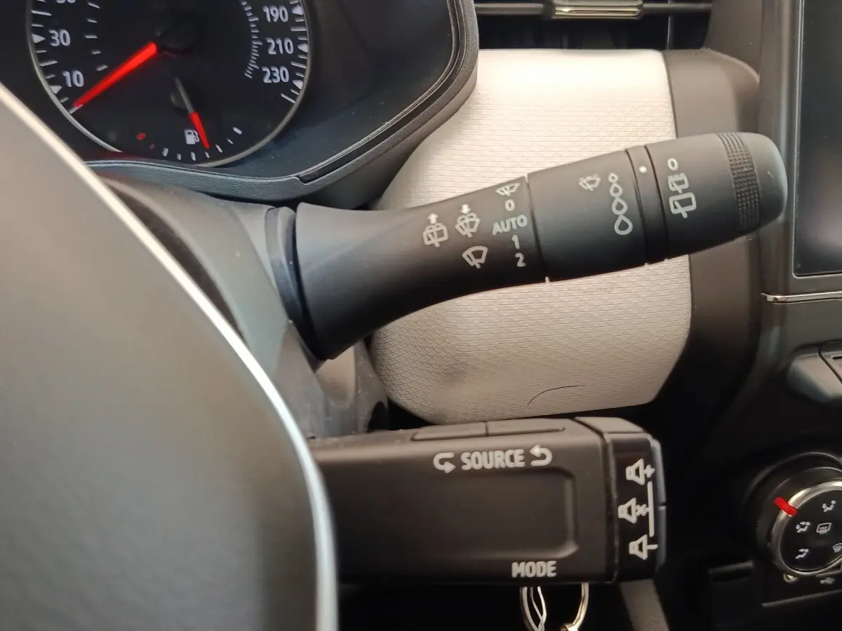Gros plan sur les commandes de volant et tableau de bord beige clair de la Renault Clio Evolution TCe 90 2023.