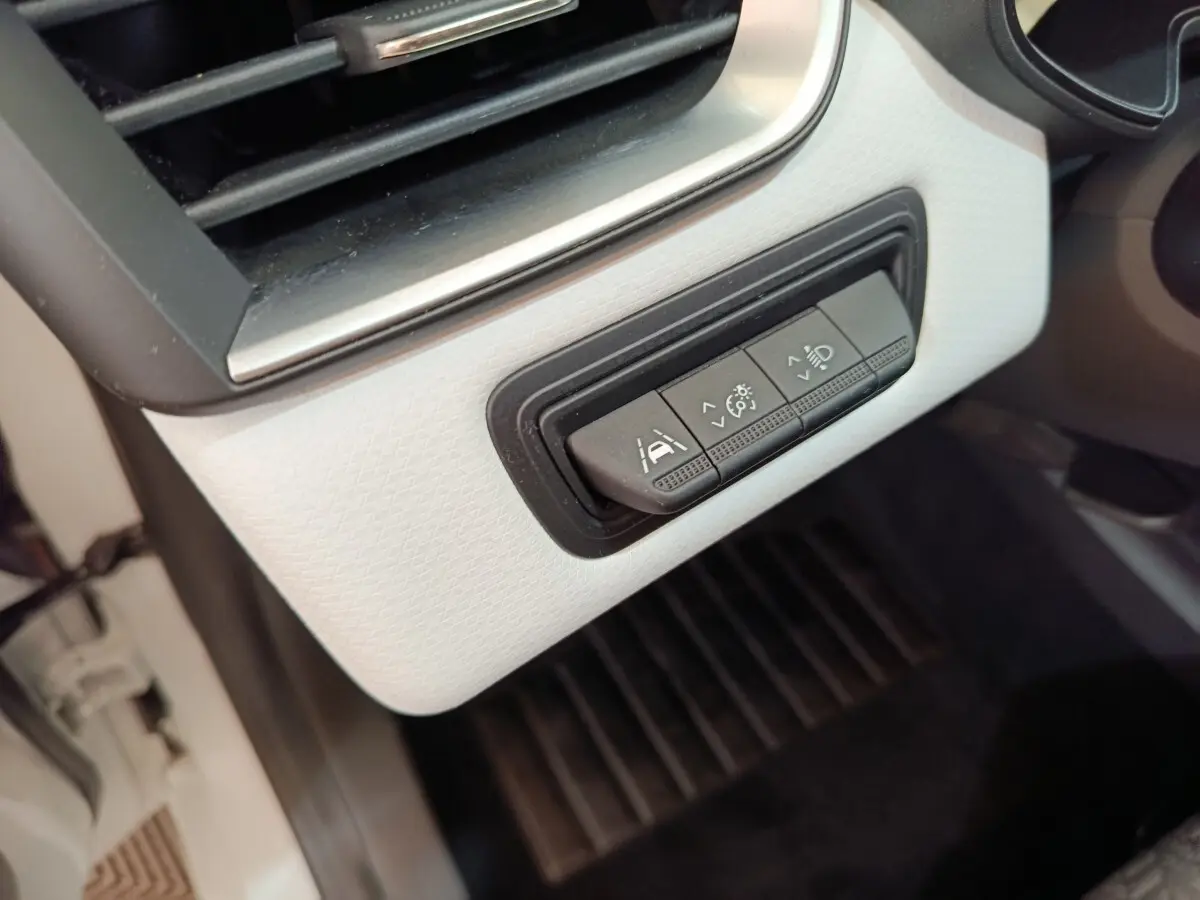 Gros plan sur les commandes d'assistance à la conduite sur tableau de bord blanc de la Renault Clio Evolution TCe 90.