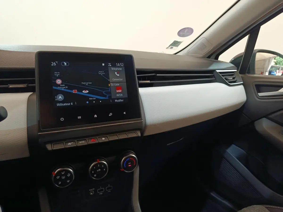 Vue intérieure de la planche de bord de la Renault Clio Evolution TCe 90 2023 avec écran tactile et garniture claire.