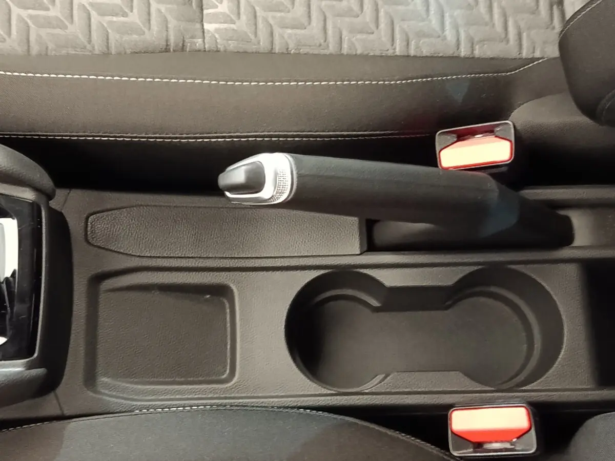 Vue plongeante sur la console centrale noire de la Renault Clio Evolution TCe 90 avec frein à main et porte-gobelets.