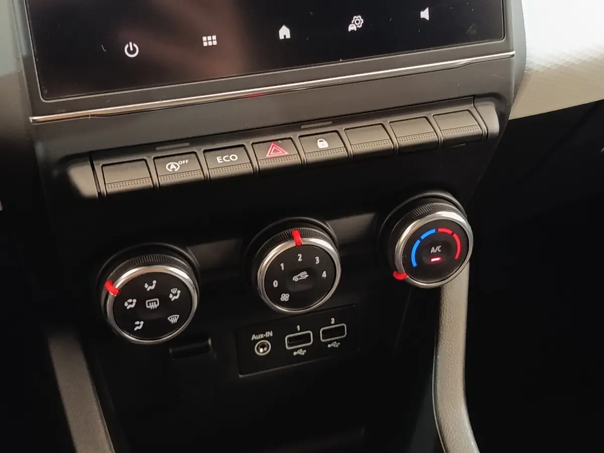 Gros plan sur les commandes de climatisation et boutons de fonction du tableau de bord de la Renault Clio blanche 2023.