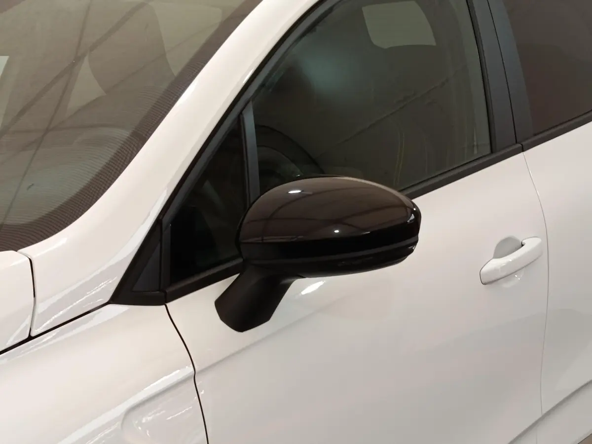 Gros plan sur le rétroviseur noir côté gauche d'une Renault Clio Evolution TCe 90 blanche de 2023.