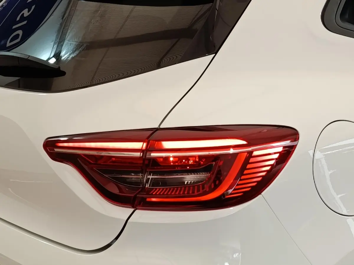 Gros plan sur le feu arrière droit rouge allumé d’une Renault Clio blanche Evolution TCe 90 de 2023.