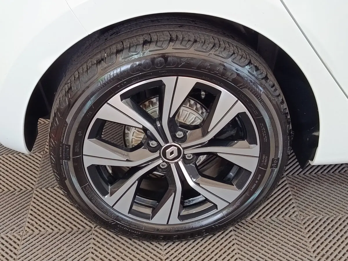 Gros plan sur la roue avant droite d'une Renault Clio blanche, avec jante alliage bicolore et pneu Goodyear.