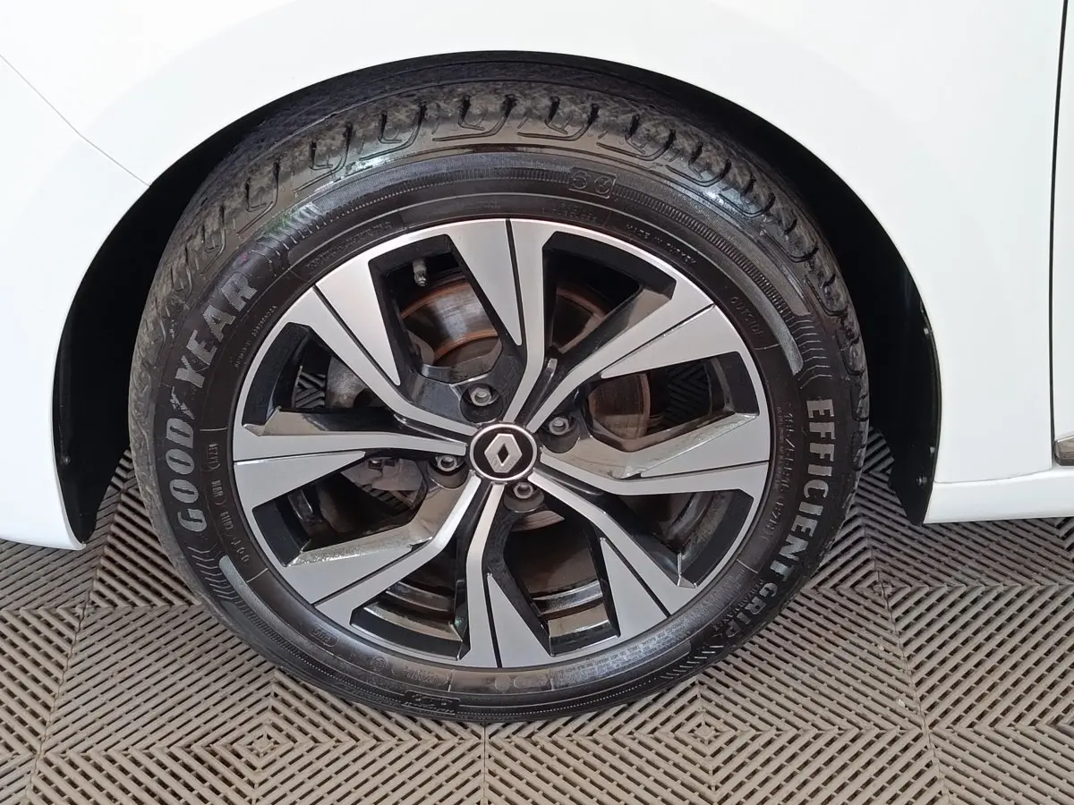 Gros plan sur la roue avant droite d'une Renault Clio blanche avec jante alliage bicolore et logo central Renault.
