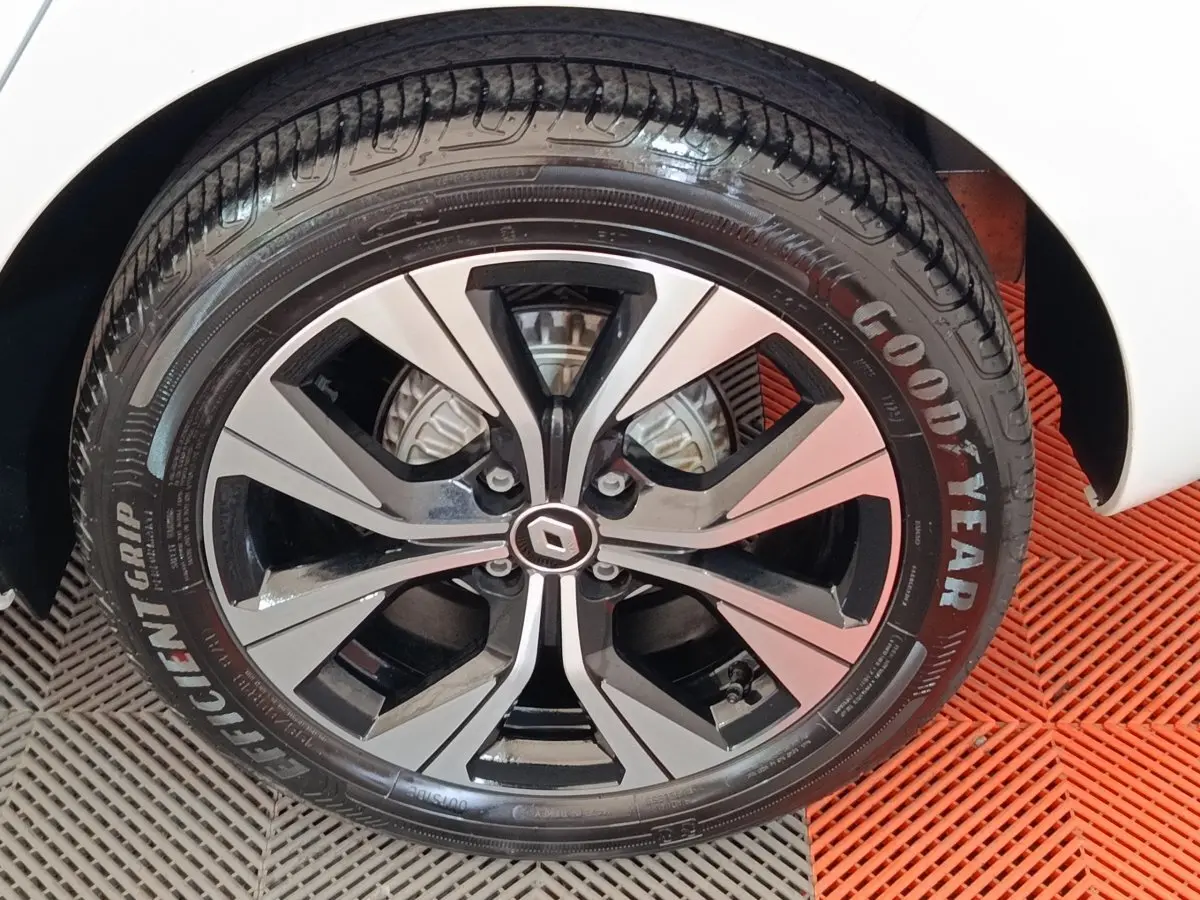 Gros plan sur la roue avant droite d’une Renault Clio blanche, jante alliage bicolore et pneu Goodyear.