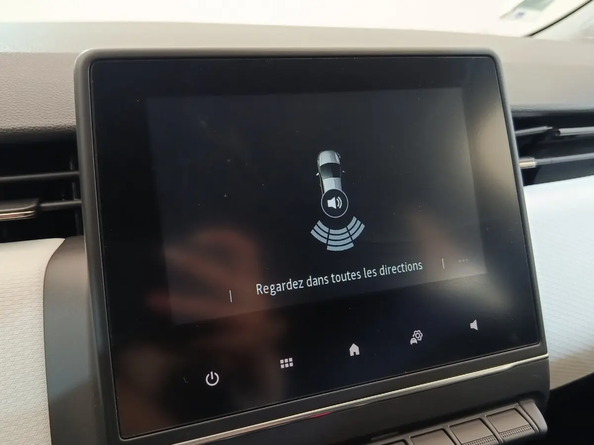 Écran tactile central de la Renault Clio blanc 2023 affichant l'alerte de surveillance des angles morts.
