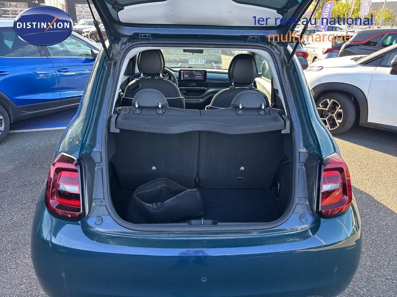 Vue arrière d'une FIAT 500 électrique 2023 vert océan métal avec coffre ouvert montrant l'intérieur et les sièges noirs.