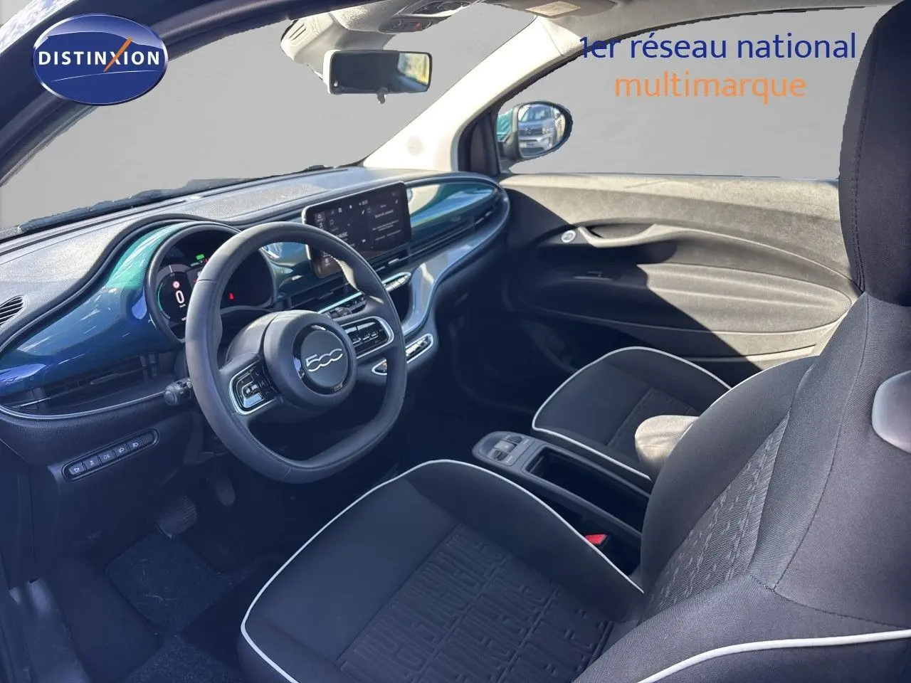 Vue intérieure côté conducteur de la Fiat 500 électrique 2023 avec tableau de bord vert océan métallisé et sièges noirs.