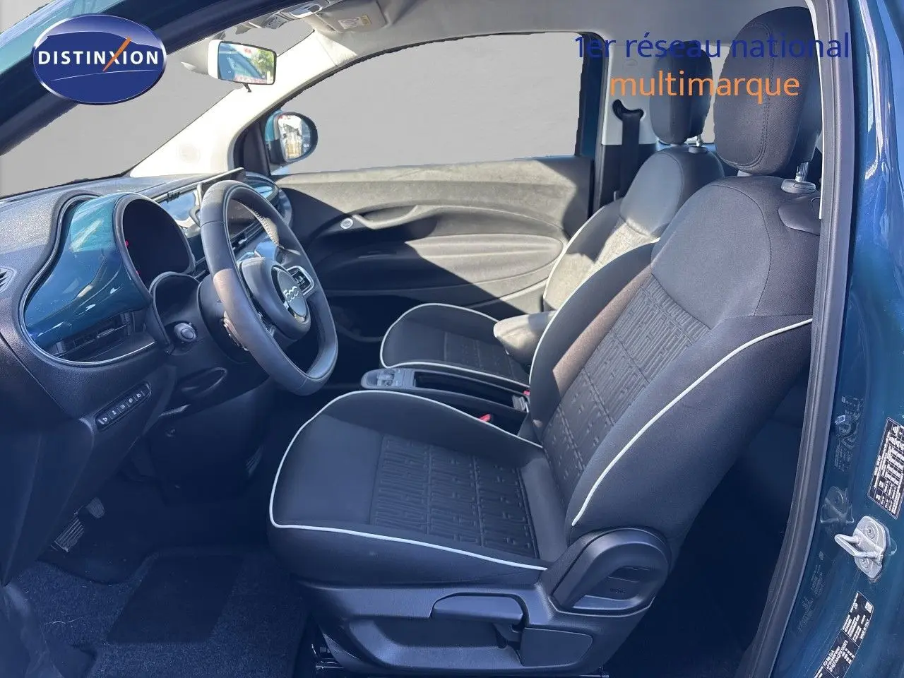 Intérieur côté conducteur de la FIAT 500 Electrique 2023 en vert océan, sièges tissu noir avec surpiqûres blanches.