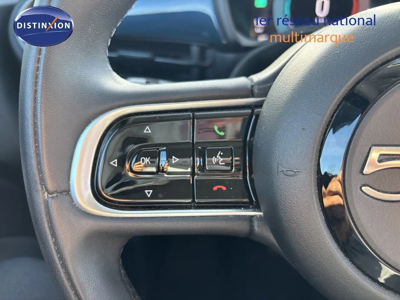 Gros plan sur les commandes gauche du volant noir de la FIAT 500 électrique 2023, mettant en valeur les boutons multifonctions.