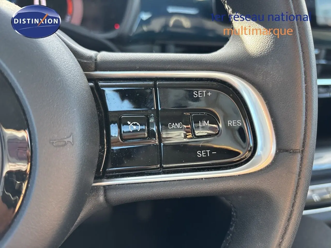 Gros plan sur les commandes de régulateur de vitesse au volant cuir d'une FIAT 500 électrique 2023.