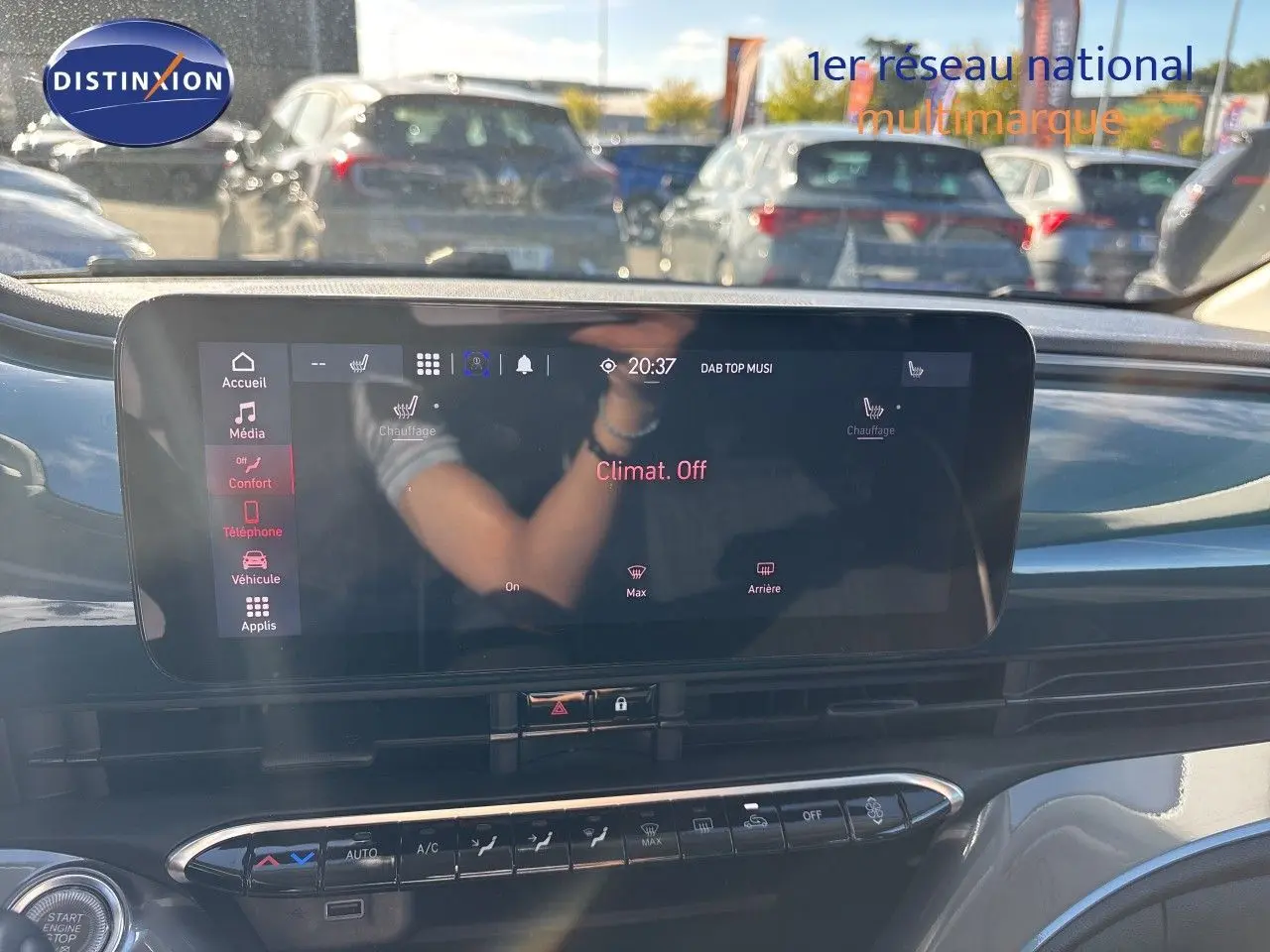 Vue intérieure centrée sur l'écran tactile du tableau de bord de la FIAT 500 électrique, avec reflet et commandes climatisation visibles.