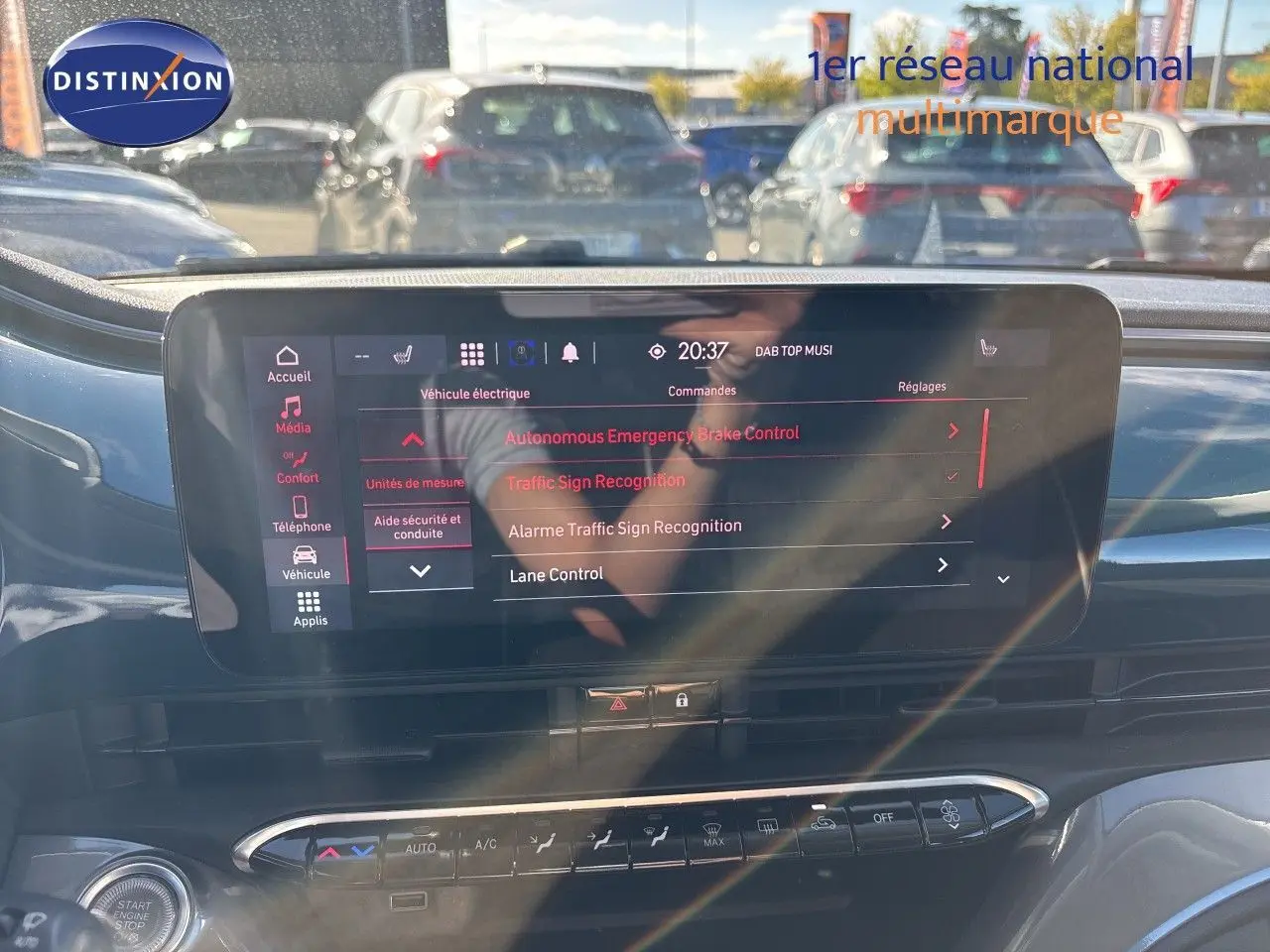 Écran tactile central de la Fiat 500 électrique 2023, vue intérieure avant avec reflets et commandes climatisation visibles.