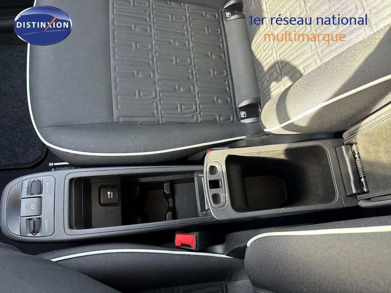 Vue rapprochée de la console centrale et des sièges en tissu noir avec surpiqûres blanches d'une Fiat 500 électrique 2023.