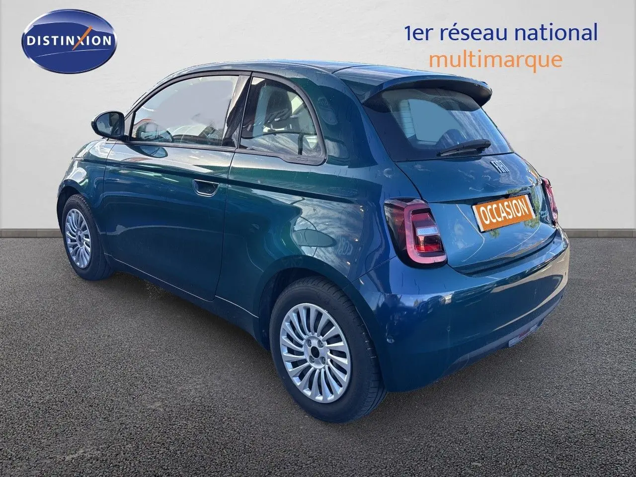 Vue 3/4 arrière droite d'une FIAT 500 électrique 2023 en vert océan métallisé avec jantes multibranches et feux arrière LED.