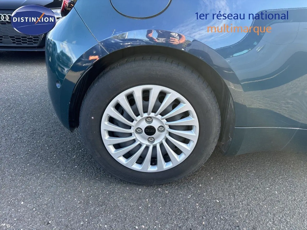Gros plan sur la roue arrière droite d'une FIAT 500 électrique 2023 vert océan métal avec jante argentée multibranches.