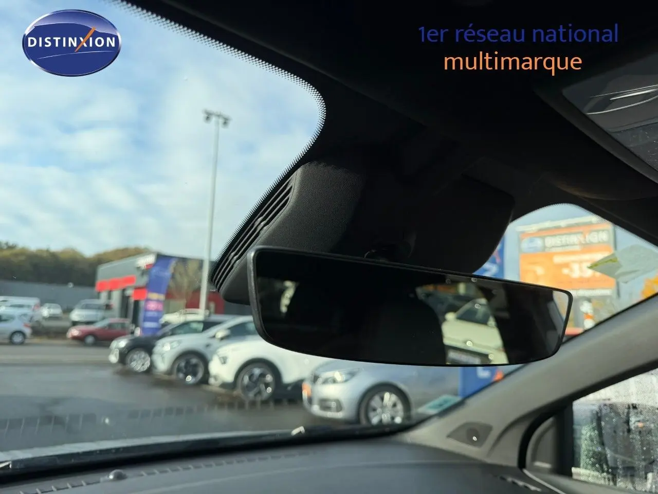 Vue intérieure du rétroviseur central d'un MG3 1.5 Hybrid 2024, avec aperçu flou du parking extérieur.