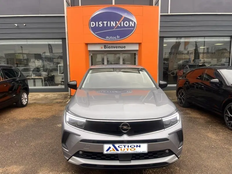 Vue avant d'un Opel Grandland gris Kontrast métallisé garé devant une concession avec calandre noire brillante et phares LED.