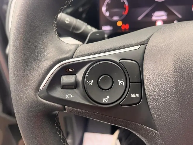 Gros plan sur les commandes noires du volant cuir multifonction de l'Opel Grandland 2023, côté gauche.