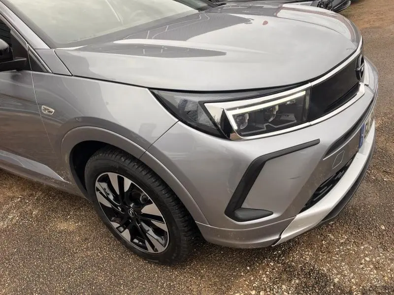 Vue 3/4 avant droit d'un Opel Grandland gris Kontrast métallisé, mettant en valeur le phare LED et la jante bi-ton 18 pouces.