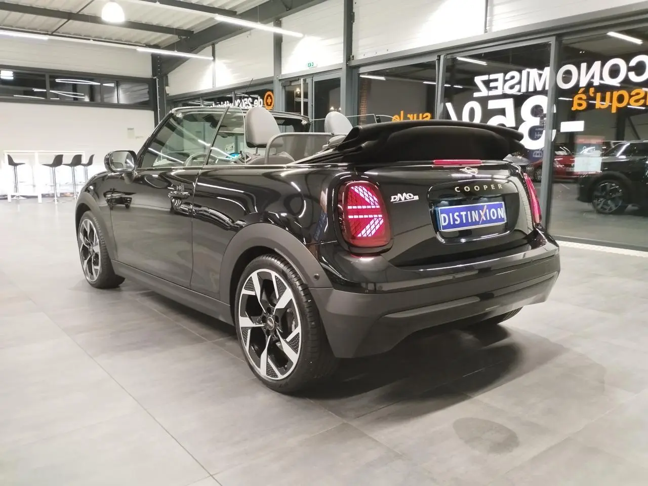 Vue 3/4 arrière droite d'une MINI Cabriolet noire avec capote souple repliée et feux arrière à LED Union Jack.