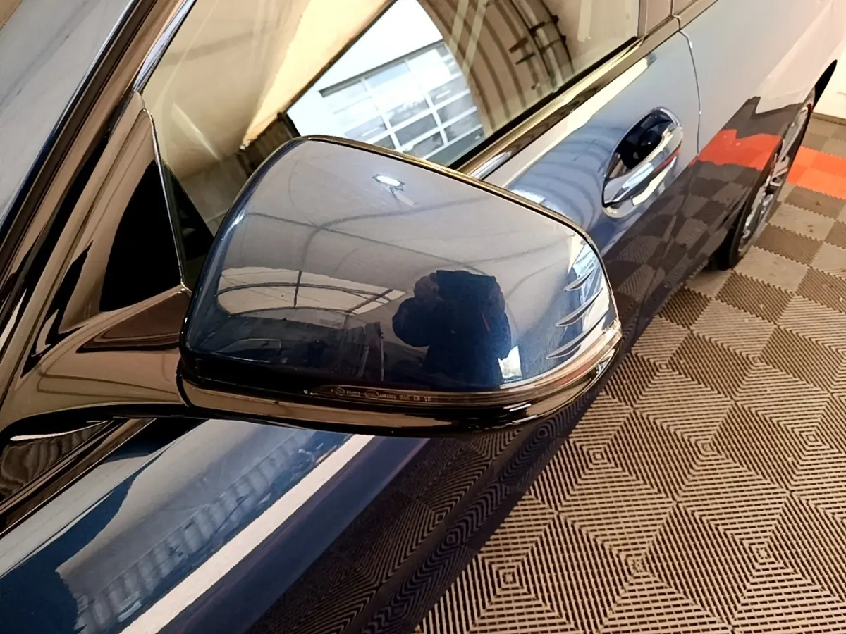 Gros plan sur le rétroviseur droit bleu métallisé de la BMW Série 1 118i Edition Sport 2023, avec poignée de porte visible.