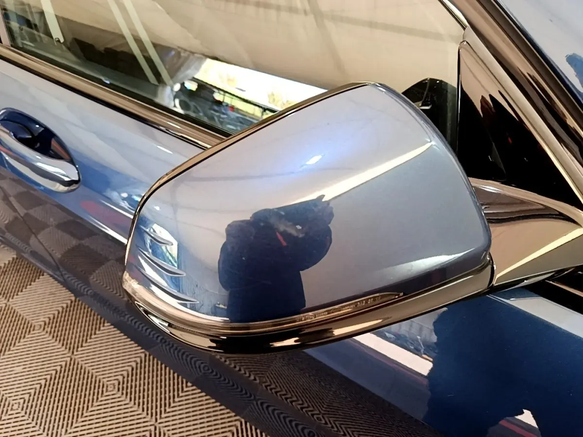 Rétroviseur côté gauche bleu métallisé de la BMW Série 1 118i Edition Sport 2023 avec poignée de porte assortie.