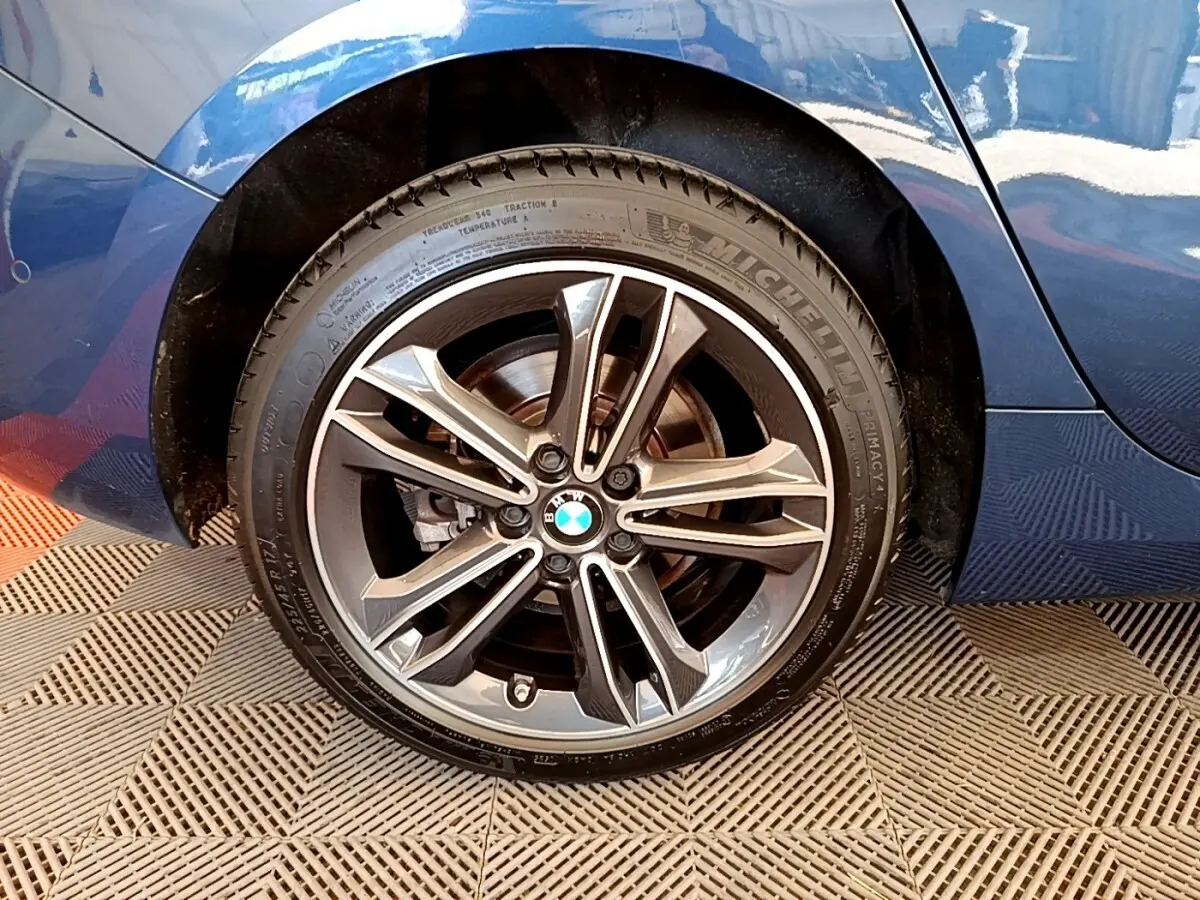 Gros plan sur la roue arrière droite d'une BMW Série 1 bleu avec jante alliage et pneu Michelin.